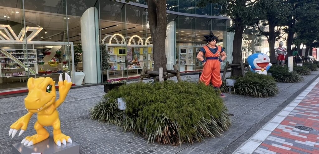 Objects displayed outside the Bandai headquarters building include ``Agumon'', ``Son Goku'', ``Doraemon'', ``Ultraman'', ``Kamen Rider'', etc.